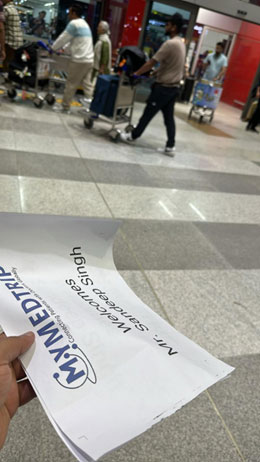 Team with placard with name on it receives the patient at the airport